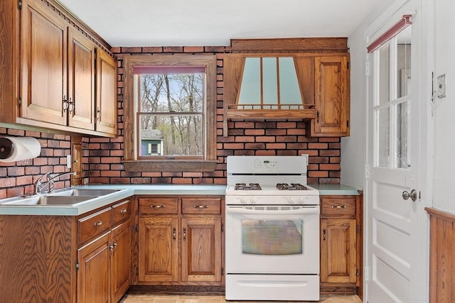 kitchen featuring a sink, light countertops, brown cabinetry, white gas stove, and custom range hood