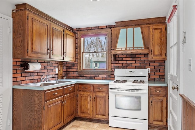 kitchen featuring brown cabinets, white gas range oven, a sink, light countertops, and custom range hood