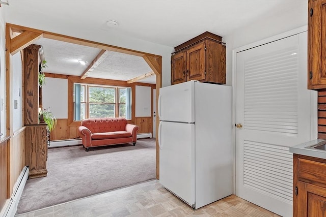 kitchen featuring freestanding refrigerator, a baseboard radiator, wooden walls, and light carpet