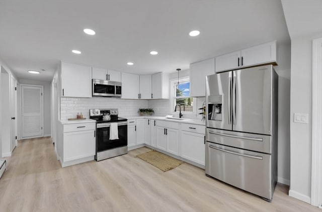 69 Notre Dame St, Springfield, MA 01104 - kitchen with stainless steel appliances, white cabinetry, light countertops, backsplash, and light wood-style floors