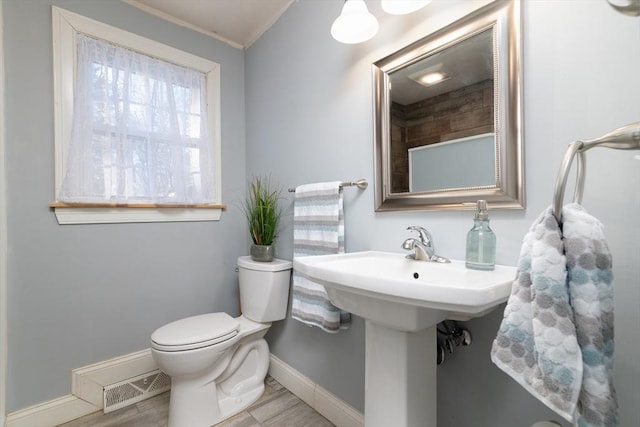 bathroom featuring ornamental molding and toilet