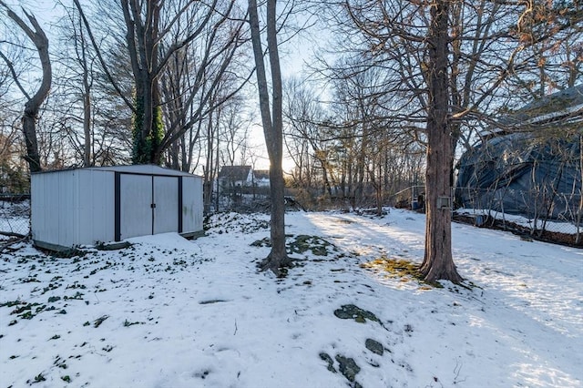 yard layered in snow featuring a shed