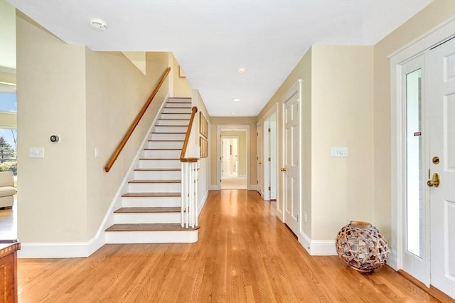foyer entrance with baseboards, recessed lighting, light wood finished floors, and stairway