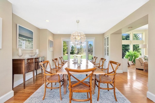 dining area with baseboards, recessed lighting, light wood-style flooring, and a notable chandelier