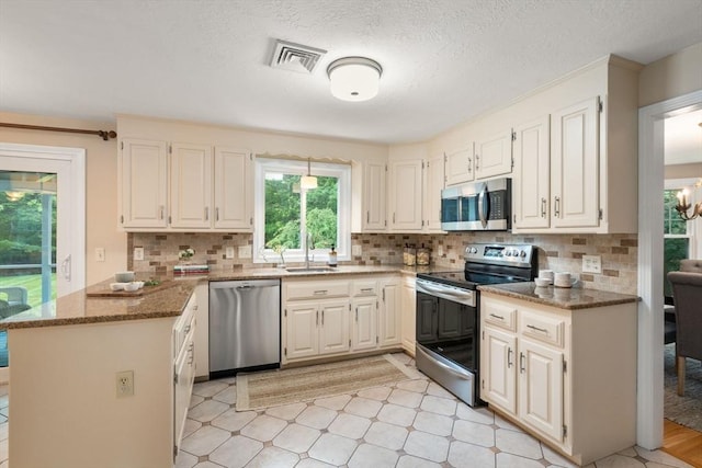 6 Magnolia Cir, Norfolk, MA 02056 - kitchen with appliances with stainless steel finishes, a peninsula, stone counters, decorative backsplash, and a textured ceiling