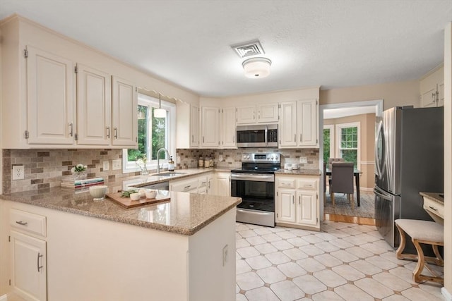 6 Magnolia Cir, Norfolk, MA 02056 - kitchen with appliances with stainless steel finishes, light stone counters, a peninsula, backsplash, and white cabinets