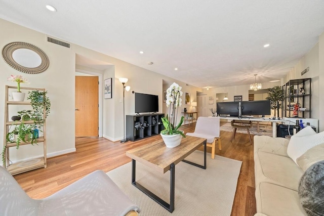living room with wood finished floors, visible vents, baseboards, recessed lighting, and a notable chandelier
