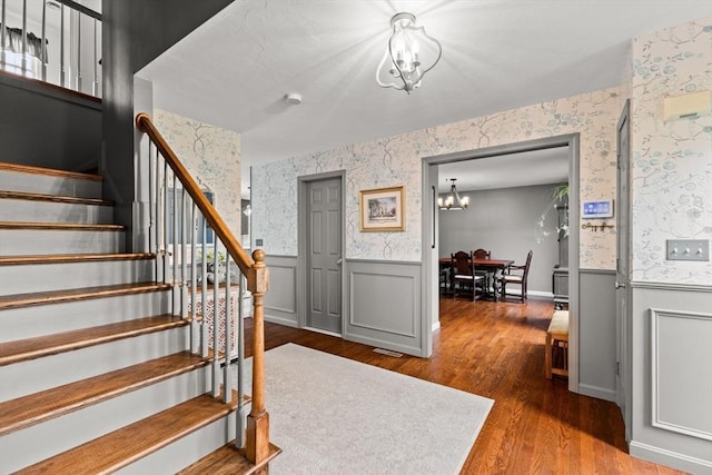 42 Britton St, Raynham, MA 02767 - stairway featuring a chandelier, a wainscoted wall, wallpapered walls, and wood finished floors