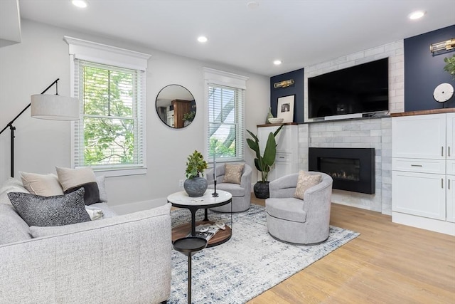 living room with light wood-style flooring, healthy amount of natural light, a fireplace, and recessed lighting