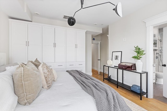 bedroom featuring light wood-style flooring and connected bathroom