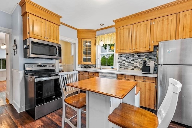 kitchen featuring stainless steel appliances, crown molding, dark wood-style floors, a sink, and light countertops