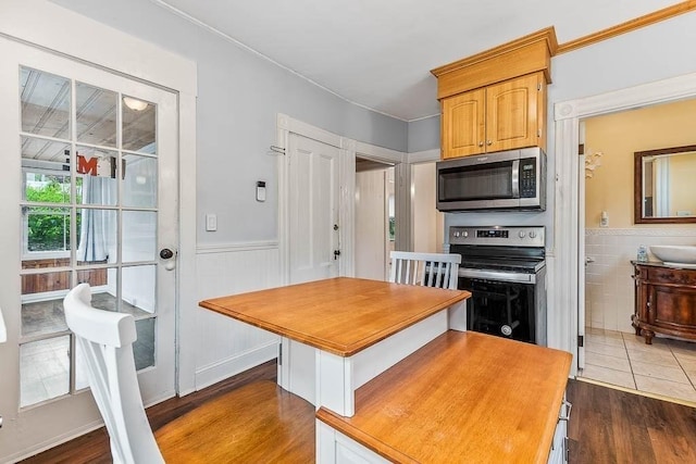 kitchen with appliances with stainless steel finishes, dark wood-style floors, and a wainscoted wall