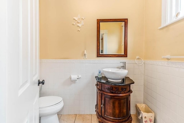 bathroom with tile walls, a wainscoted wall, tile patterned flooring, vanity, and toilet