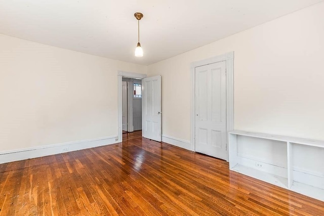 unfurnished bedroom featuring wood finished floors, baseboards, and a closet