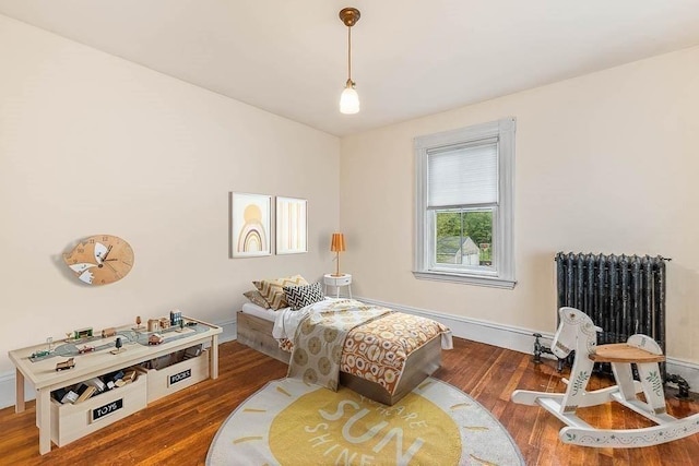 bedroom featuring radiator heating unit, wood finished floors, and baseboards
