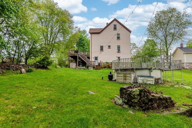rear view of property featuring a wooden deck, stairway, and a lawn