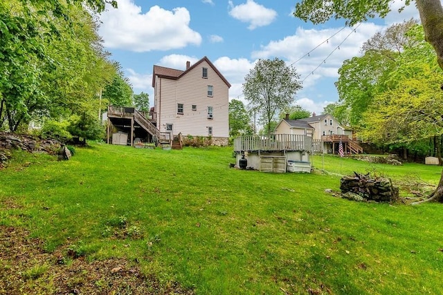 rear view of house with a deck, stairs, and a yard
