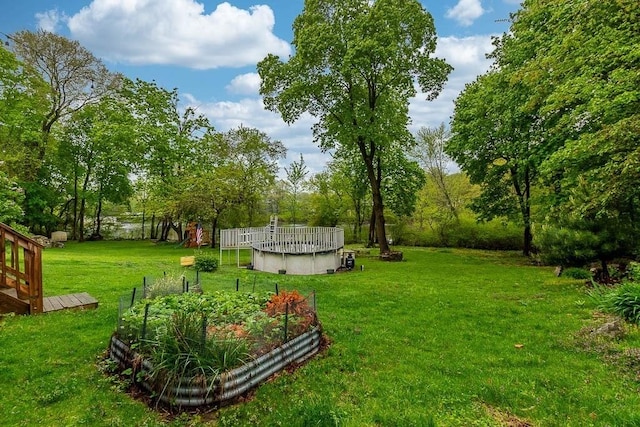 view of grassy yard with a garden, an outdoor pool, and view of scattered trees