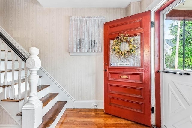 entryway featuring wood finished floors, stairs, and wallpapered walls