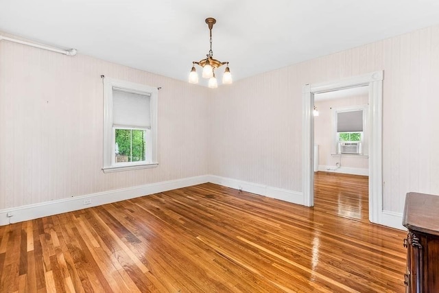 unfurnished room featuring light wood-type flooring, a chandelier, cooling unit, and baseboards