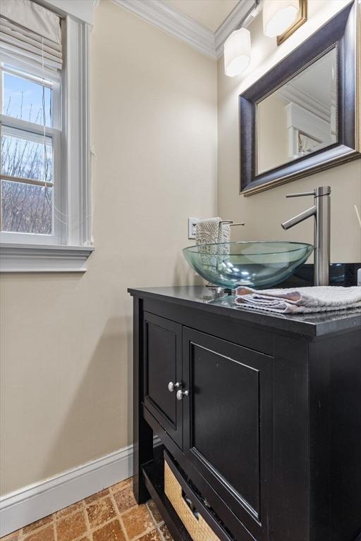 bathroom featuring baseboards, ornamental molding, and vanity