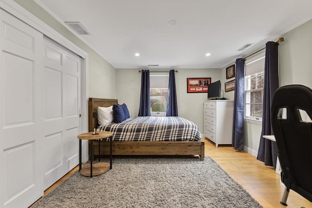 bedroom with visible vents, light wood-style floors, and multiple windows