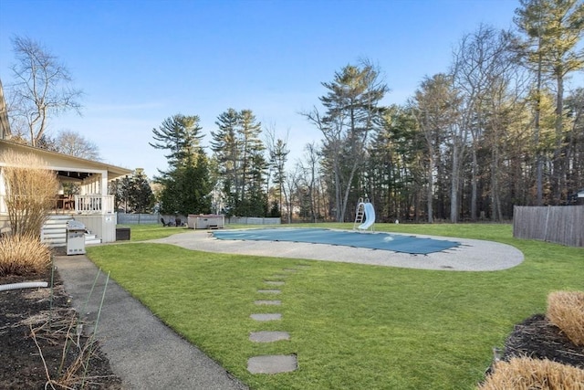 view of pool with a fenced in pool, fence, a water slide, and a yard
