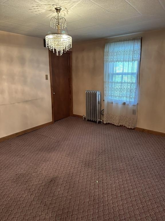 50 Keene St, Lowell, MA 01852 - spare room with radiator, a chandelier, and dark carpet