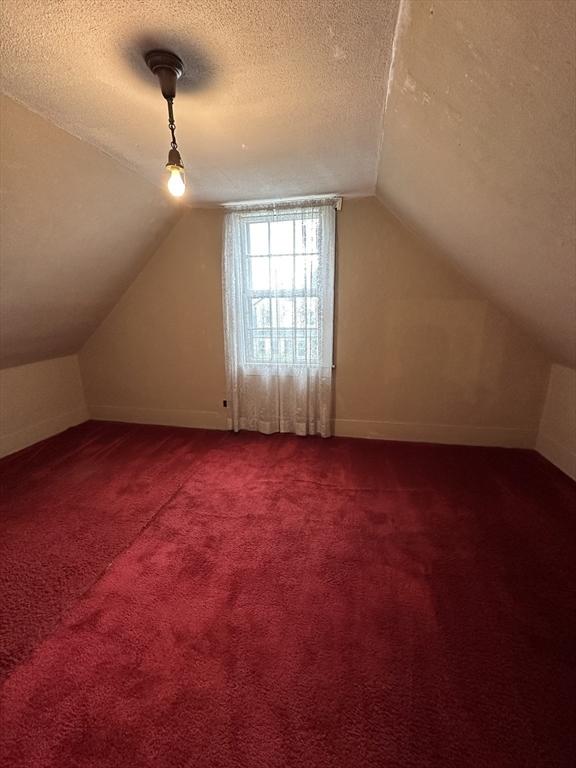 50 Keene St, Lowell, MA 01852 - additional living space with a textured ceiling, lofted ceiling, and light colored carpet