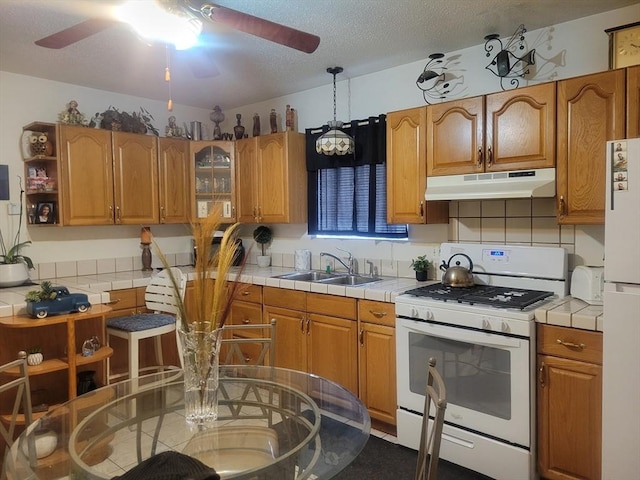 kitchen featuring tile countertops, sink, hanging light fixtures, white appliances, and a textured ceiling