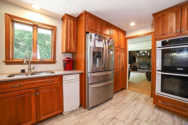40 Old Stage Rd, Chelmsford, MA 01824 - kitchen with stainless steel refrigerator with ice dispenser, multiple ovens, a sink, brown cabinets, and light stone counters