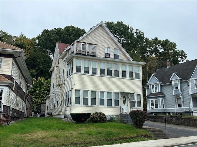 view of front of property with a balcony and a front yard