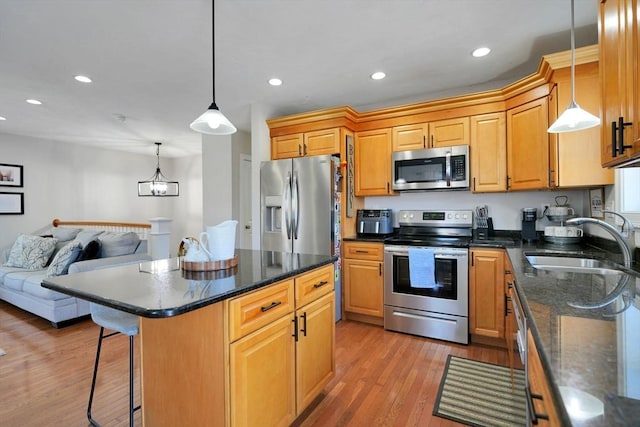 kitchen featuring open floor plan, stainless steel appliances, a sink, and pendant lighting