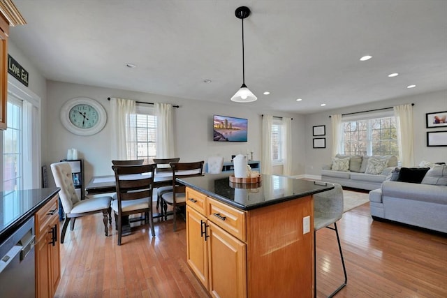 kitchen with pendant lighting, a breakfast bar area, stainless steel dishwasher, open floor plan, and a kitchen island