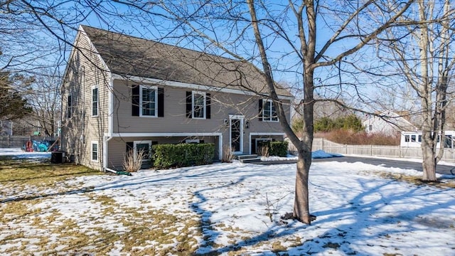 split foyer home with a shingled roof and fence