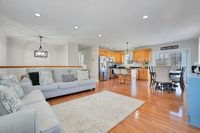 living area with light wood finished floors, an inviting chandelier, and recessed lighting