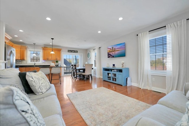 living area featuring baseboards, light wood finished floors, visible vents, and recessed lighting