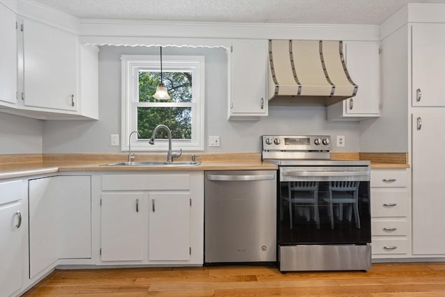 kitchen with extractor fan, light wood-style flooring, stainless steel appliances, a sink, and light countertops