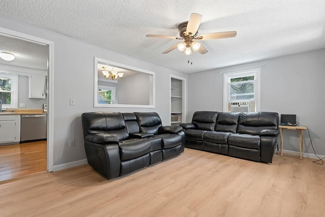 living area featuring light wood-type flooring, plenty of natural light, a textured ceiling, and baseboards