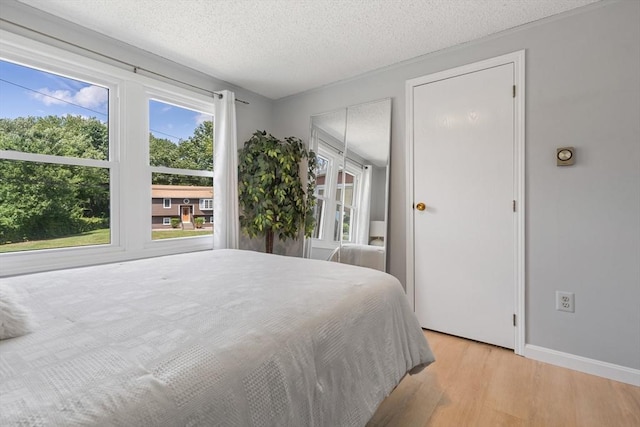 bedroom with light wood-type flooring, baseboards, and a textured ceiling