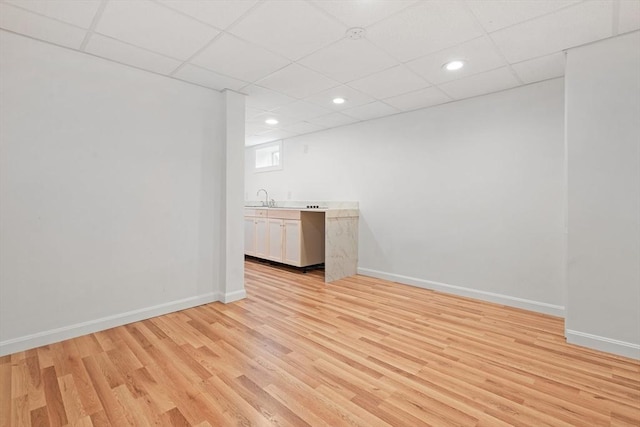 unfurnished room with a sink, light wood-style flooring, and baseboards