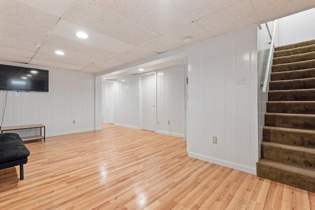 finished basement with recessed lighting, stairway, light wood-style floors, a drop ceiling, and baseboards