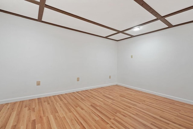 empty room featuring coffered ceiling, baseboards, and light wood finished floors