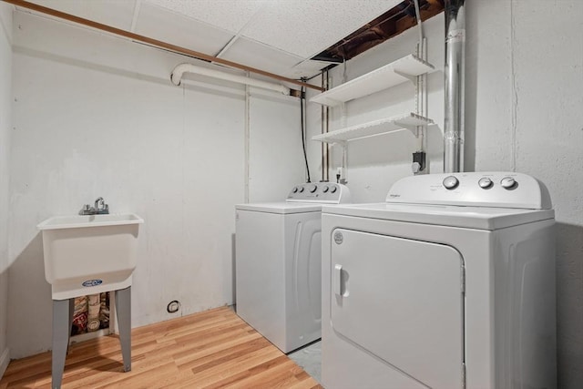 clothes washing area with laundry area, washing machine and clothes dryer, and light wood-style floors