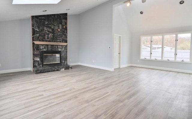 unfurnished living room featuring wood finished floors, a high end fireplace, baseboards, and high vaulted ceiling