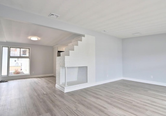 unfurnished living room featuring vaulted ceiling, light wood-style floors, baseboards, and a fireplace