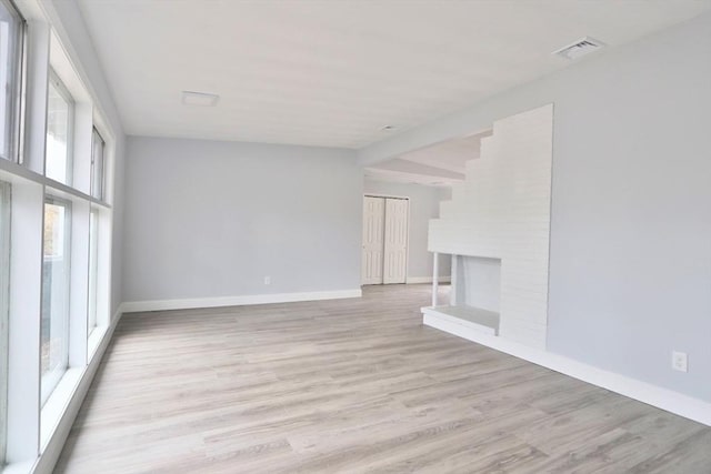 unfurnished living room featuring light wood-style floors, baseboards, and a fireplace
