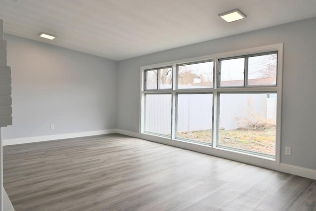 unfurnished room with baseboards, plenty of natural light, and wood finished floors