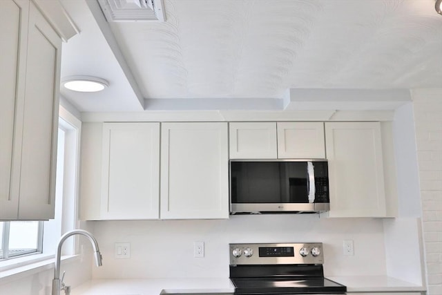 kitchen with appliances with stainless steel finishes, light countertops, and white cabinetry