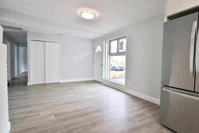 unfurnished dining area featuring light wood-style flooring and baseboards